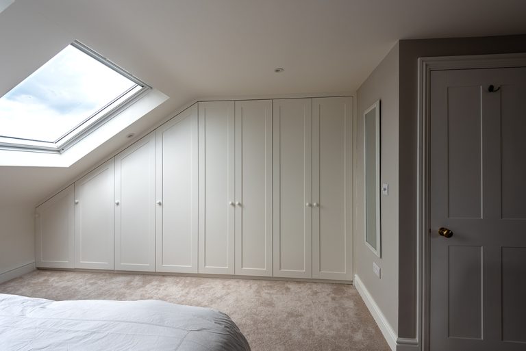 Custom-fitted Slanted Wardrobe in Loft Bedroom. Designed and installed by carpenters at Bespoke Carpentry London.