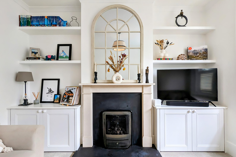 White alcove cupboards next to chimney breast with floating shelves