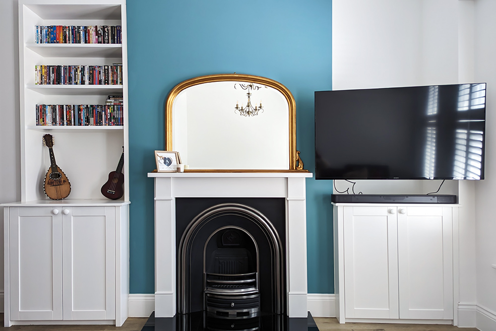 Built-in alcove cupboards either side of fireplace with a shelving unit.