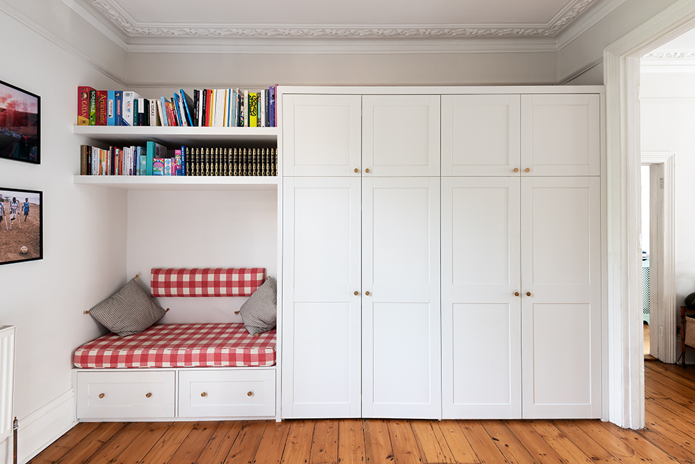 Built-in cupboard with bookshelf, desk and seating area. Designed by carpenter at Bespoke Carpentry London
