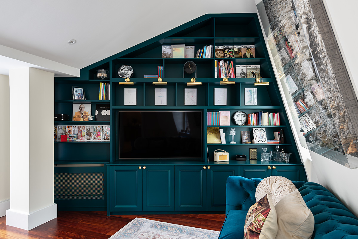 Large green slanted built in TV unit with shelving