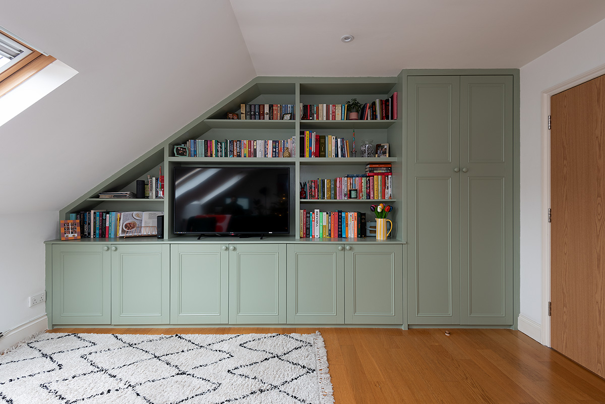 Large slanted built-in cupboard with wardrobe, bottom cupboard doors and shelving space to store TV.