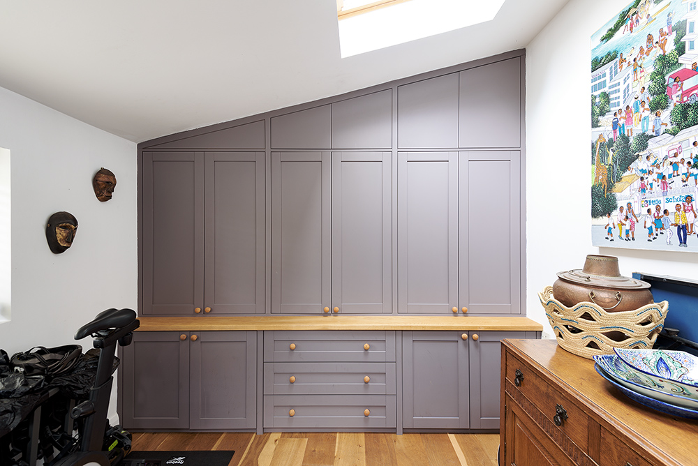 Large grey wall to wall built-in loft wardrobe with 6 doors and cupboards at the bottom. Designed and installed by Bespoke Carpentry London