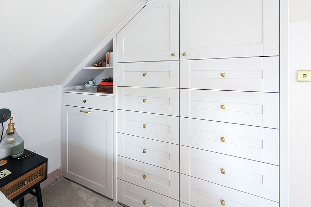 White slanted built-in wardrobe with 12 drawers.