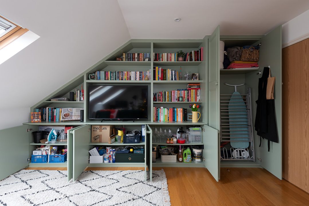 Large wall to wall media unit with storage cupboards on slanted roof. Designed and installed by Bespoke Carpentry London