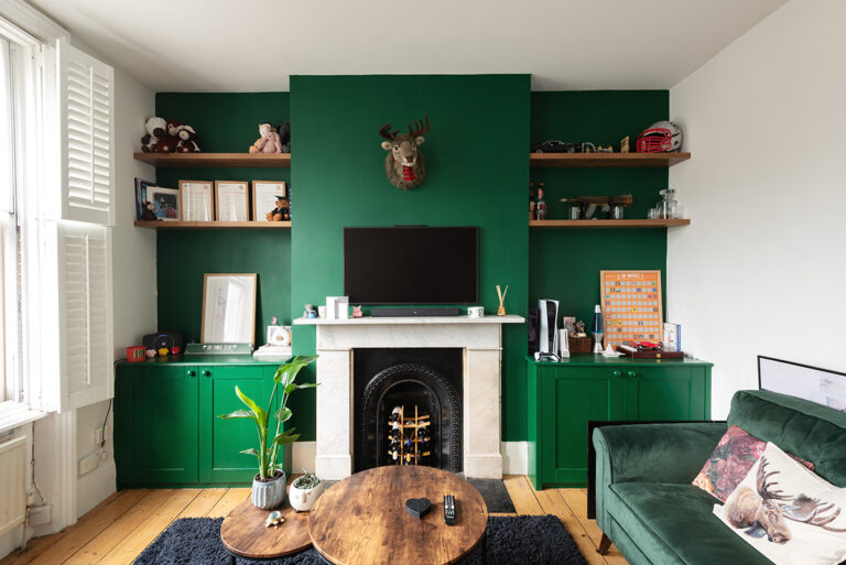 After installation picture of a green built-in alcove cupboard and shelving next to fireplace. Made by Bespoke Carpentry London.