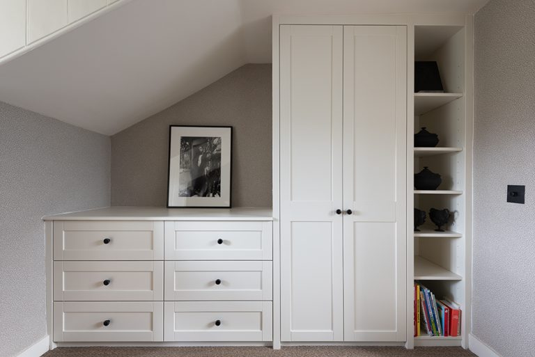 Built in wardrobe in slanted roof with chest of drawers.