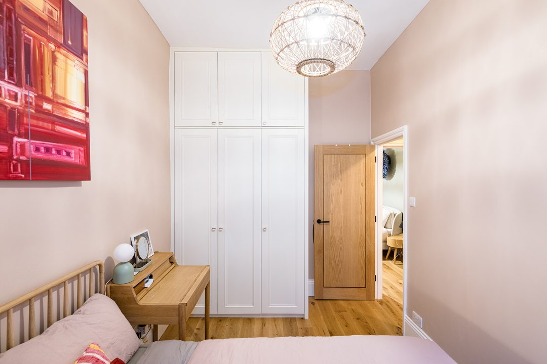 Built in 3 door wardrobe in bedroom. Built-in over door wardrobe leading to ensuite bathroom. Designed and built by carpenters and joiners at Bespoke Carpentry London.