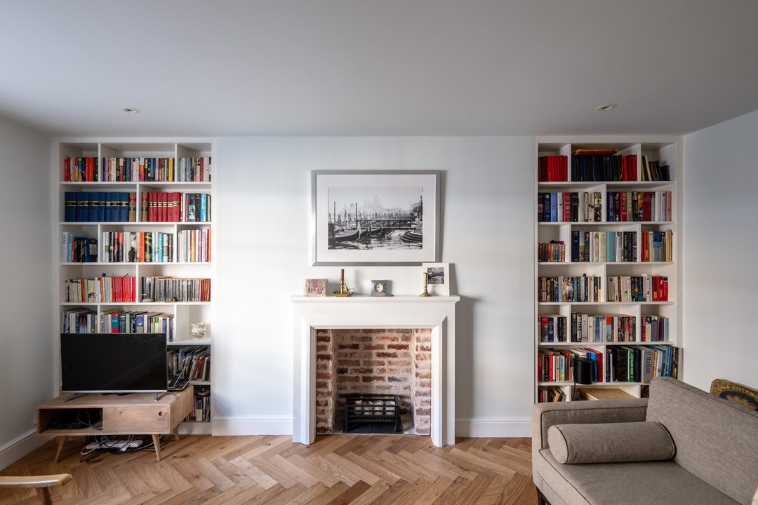Built in alcove bookshelf next to fireplace with shelving for books