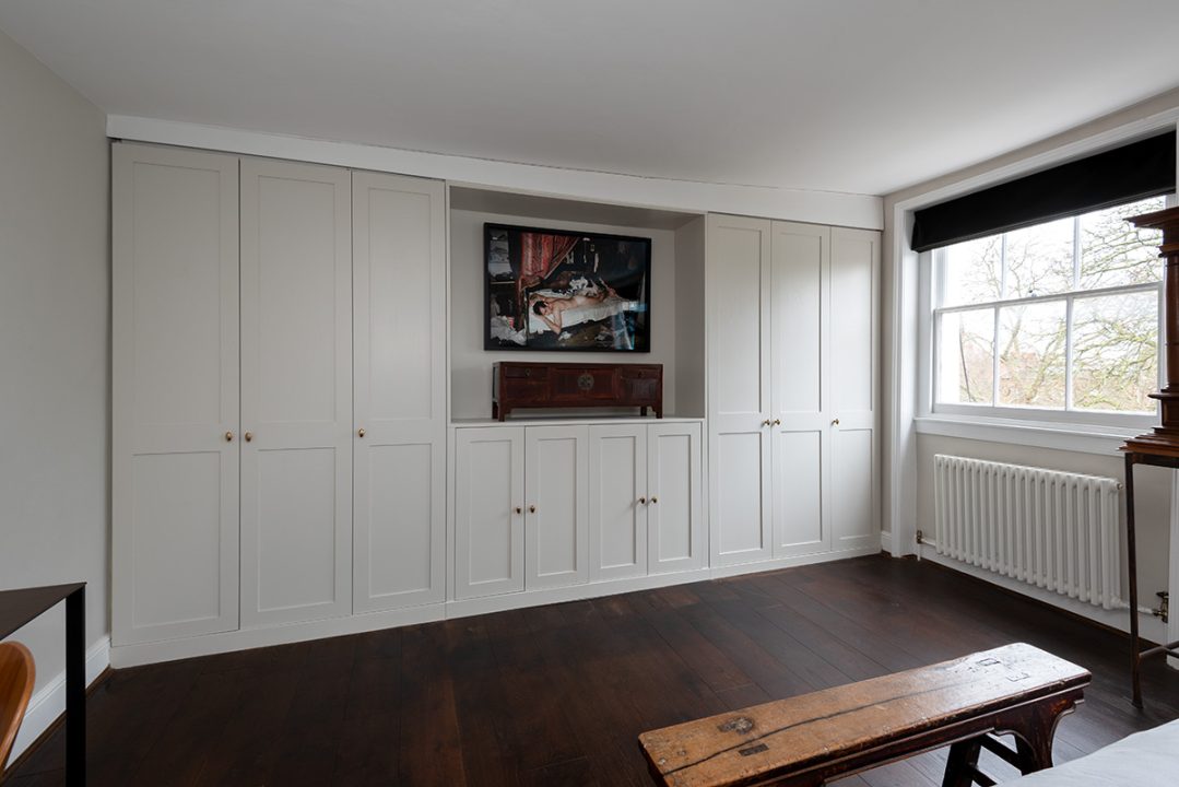 A large white modern bespoke wardrobe that goes from wall to wall with 6 doors