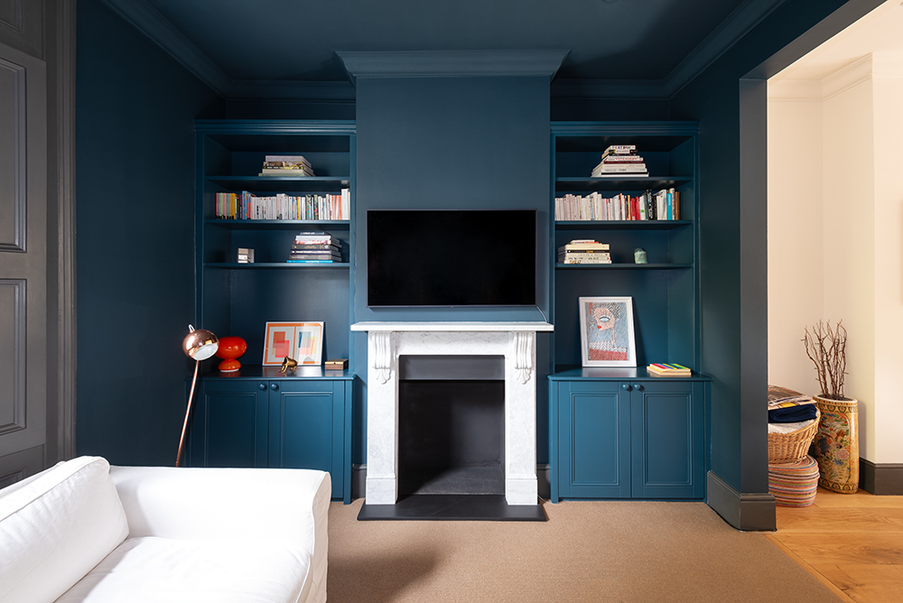 Custom made blue alcove cupboards and floating shelves in living room.