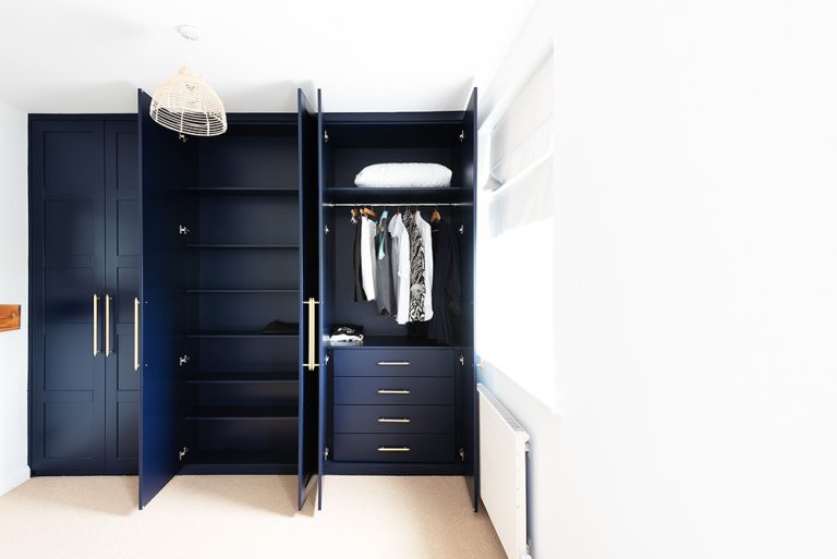 Blue bespoke wardrobe, customised for the interiors of a wardrobe with shelving, drawers and hanging rails.