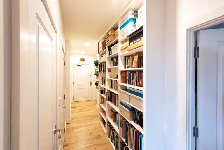 White built in bookshelf in the hallway, floor to ceiling.