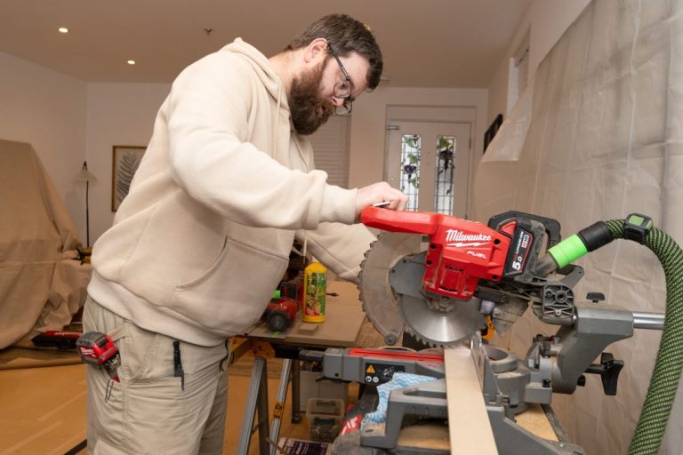 Lead carpenter cutting wood with big machine in room