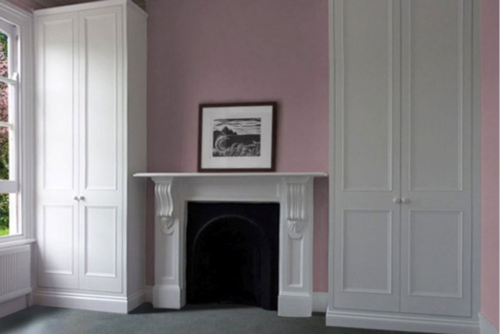 Two white fitted alcove wardrobes next to chimney